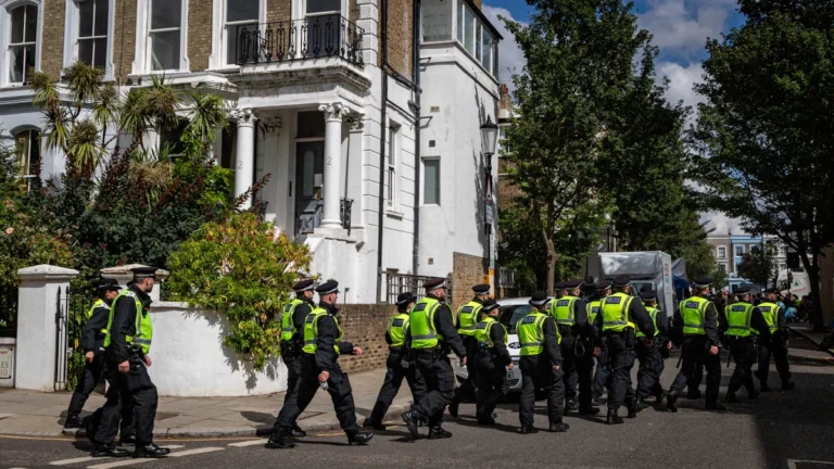 A large group of Metropolitan Police officers in high-visibility vests patrolling a residential London street.