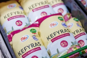 Several plastic bags of Pilos brand 5% fat kefir stacked inside a supermarket storage crate.