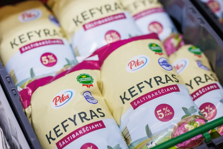 Several plastic bags of Pilos brand 5% fat kefir stacked inside a supermarket storage crate.