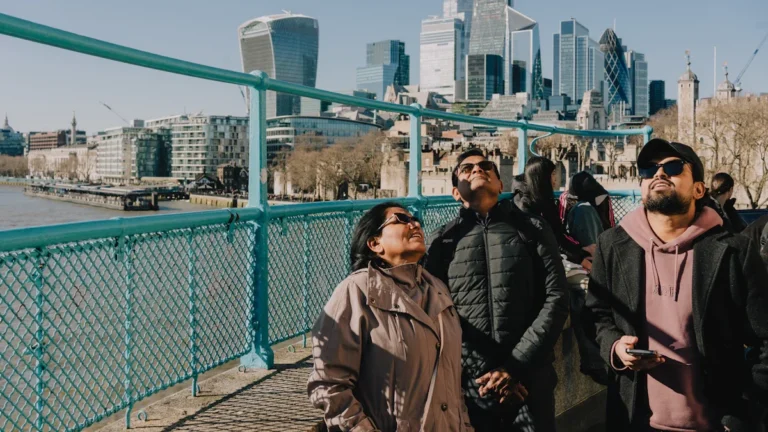 A diverse group of people of South Asian heritage enjoying the London skyline from a bridge.