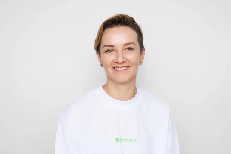 Smiling woman with short brown hair wearing a white sweatshirt against a plain light background.