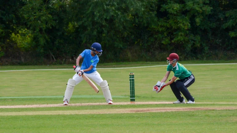A young batsman and wicketkeeper during a school cricket match in Birmingham.