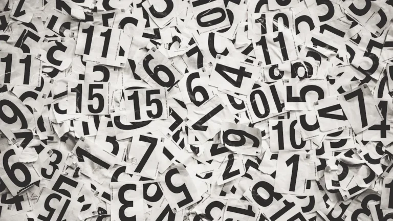 A large pile of white paper slips with black numbers printed on them, symbolizing the election counting process.