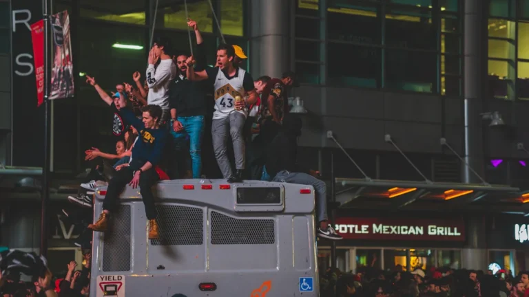 Fans celebrate on top of a bus during a victory parade at night.