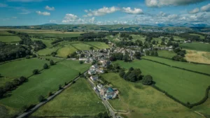An aerial view of a small rural village in Cheshire East surrounded by vast green fields and farmland.