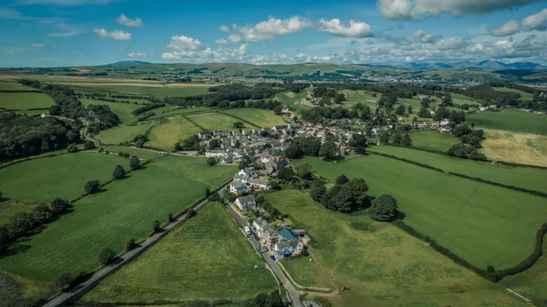An aerial view of a small rural village in Cheshire East surrounded by vast green fields and farmland.