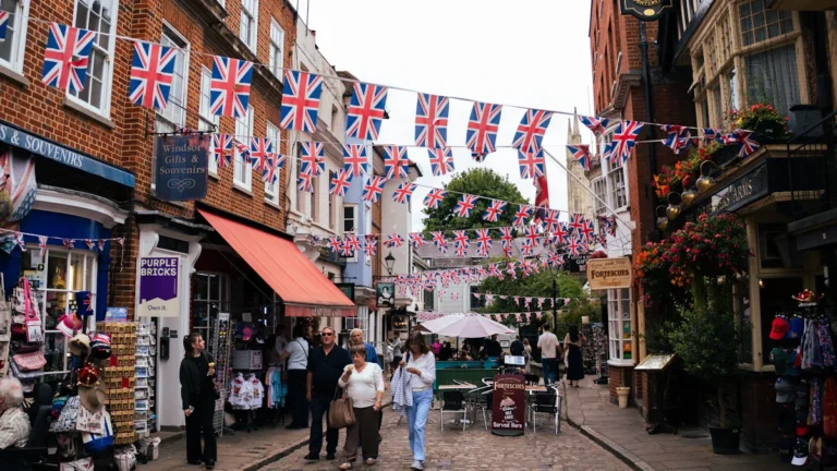 A bustling English high street with various small businesses and Union Jack bunting.
