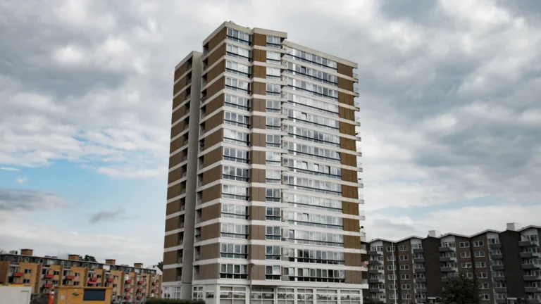 A tall residential tower block stands against a cloudy sky, representing the urban landscape of London.