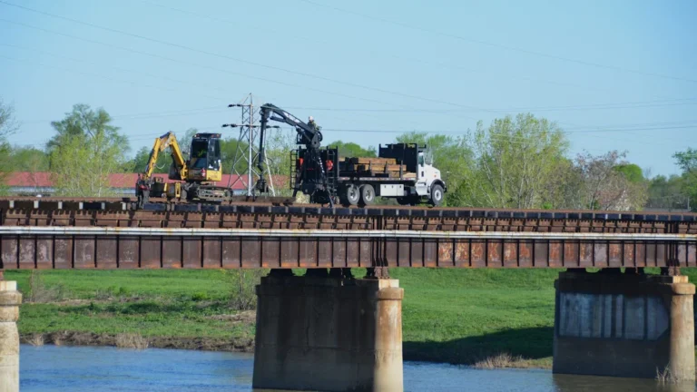 Construction machinery performing repairs on a bridge structure during the day.