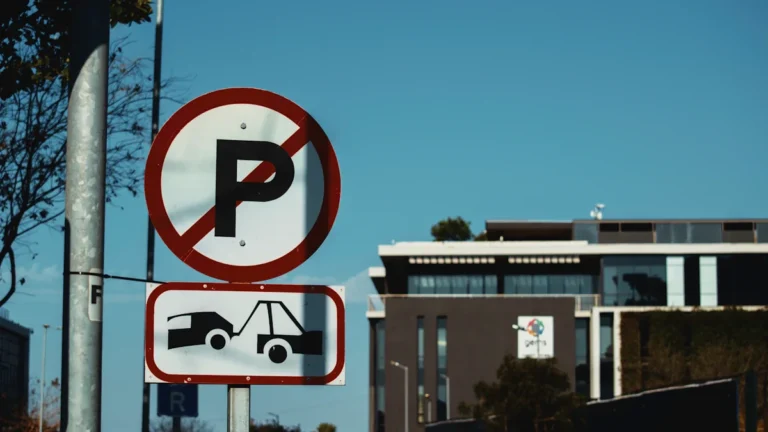 A circular no parking sign sits above a rectangular tow-away zone warning sign on a pole.