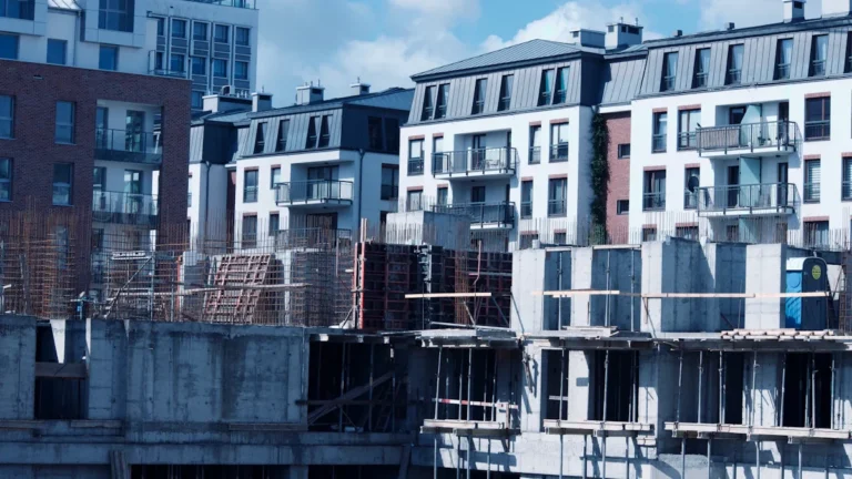A construction site in a European city with modern residential apartment buildings in the background.