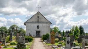 Traditional stone church surrounded by a historic cemetery with various crosses and gravestones in Lithuania.