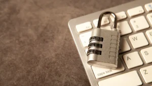 A silver combination padlock sits securely on a modern white computer keyboard.