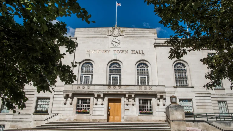 The stone facade of Hackney Town Hall featuring arched windows and a central clock.