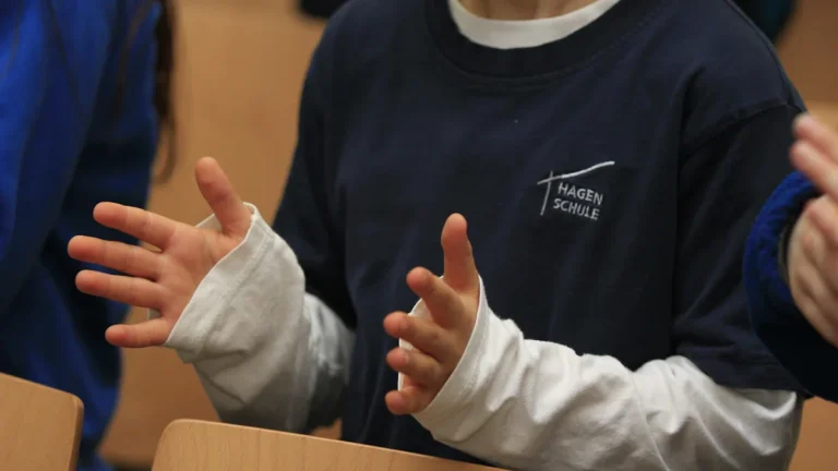 Close up of a student using sign language in a classroom setting.