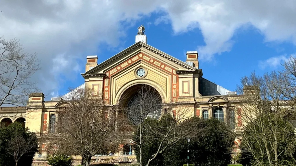 The historic exterior of Alexandra Palace in London, featuring its iconic arched window and stonework.