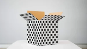 An open cardboard box with a black and white geometric arrow pattern on a white surface.