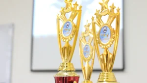 A close-up of multiple ornate gold trophies with star emblems, representing a business awards ceremony.