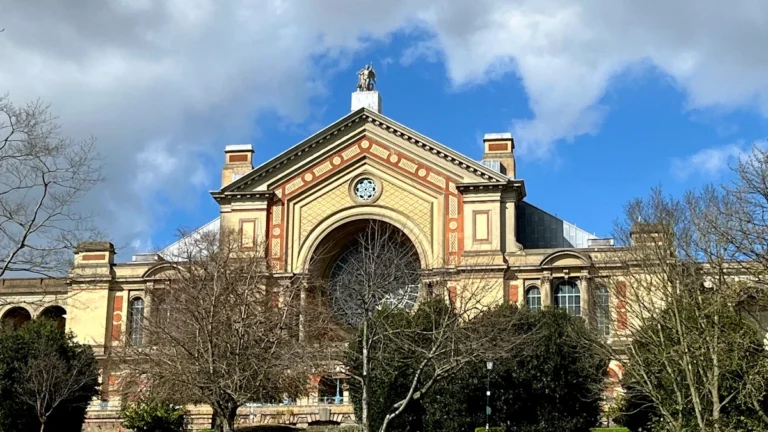 The iconic exterior facade of Alexandra Palace in North London under a blue sky.