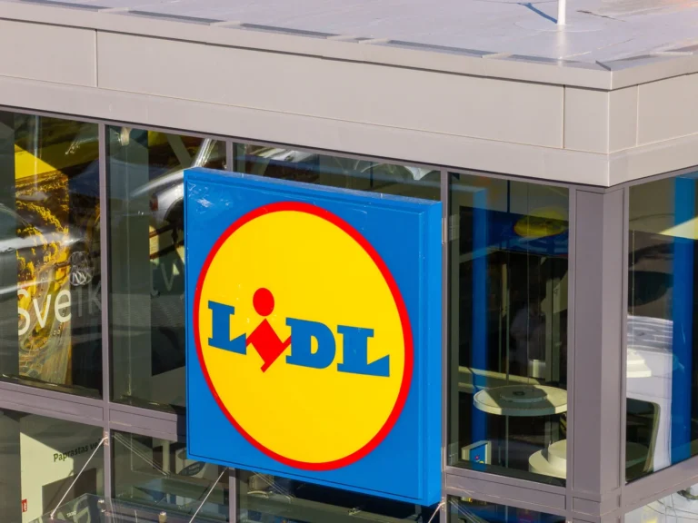 Lidl supermarket logo on a blue square sign mounted on a modern glass building facade.