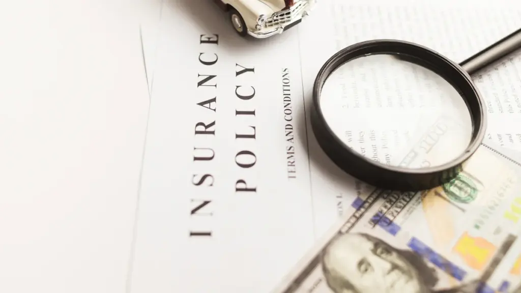 An insurance policy document with a toy car, magnifying glass and currency bills.