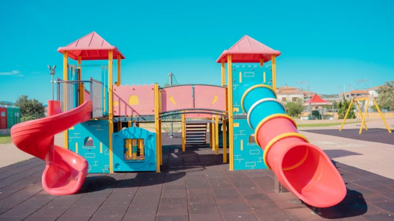 A colorful playground structure featuring towers and slides under a bright blue sky.
