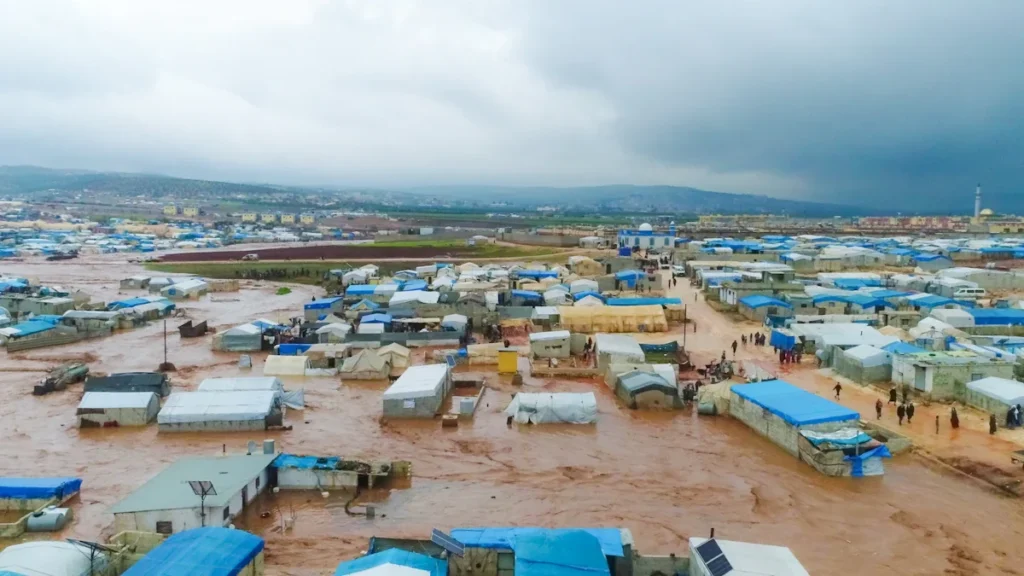 Aerial view of emergency shelters and flooded terrain illustrating the need for infrastructure investment.