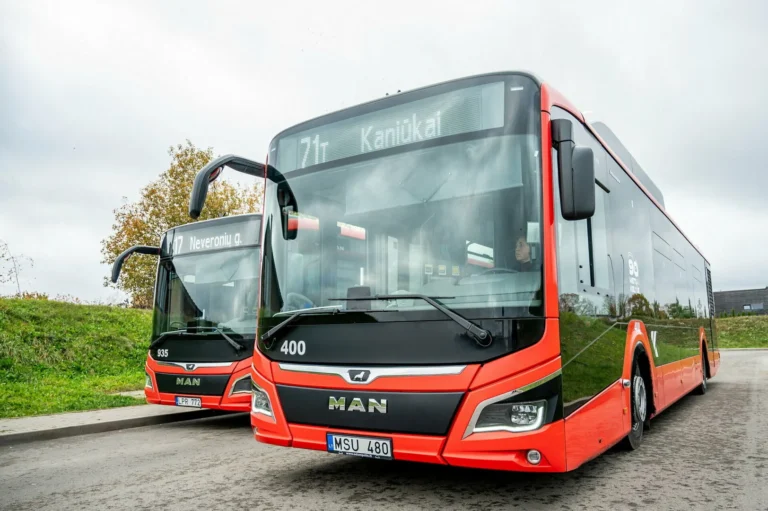 Front view of two modern red and black MAN city buses parked side-by-side.