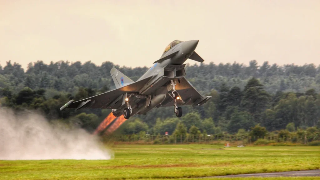A Royal Air Force Eurofighter Typhoon jet takes off from a runway with visible engine heat.