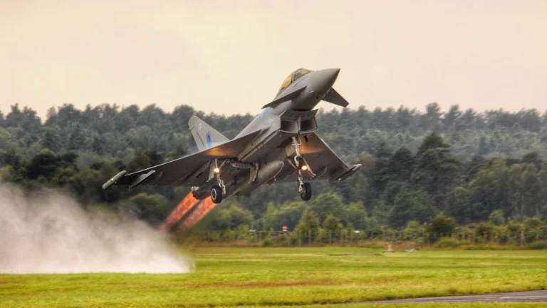 A Royal Air Force Eurofighter Typhoon jet takes off from a runway with visible engine heat.