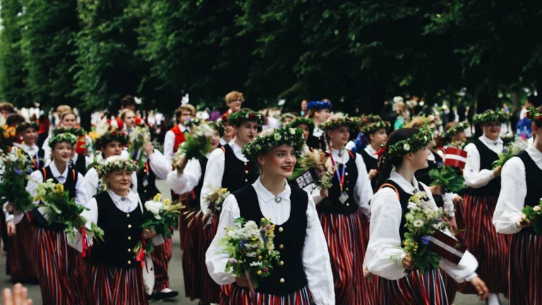 Participants in traditional Latvian folk costumes with floral wreaths celebrate the Līgo Midsummer festival.