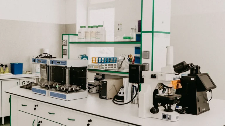 A clean, professional clinical laboratory setting featuring a microscope and scientific equipment on white countertops.
