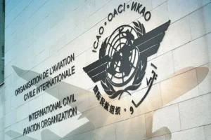 Black emblem and multilingual name of the International Civil Aviation Organization on a light stone wall.