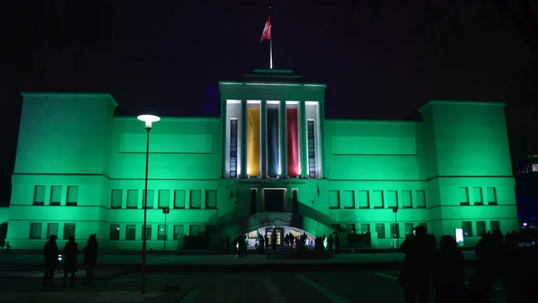 The Lithuanian Parliament building in Vilnius illuminated with the national colors of yellow, green, and red at night.