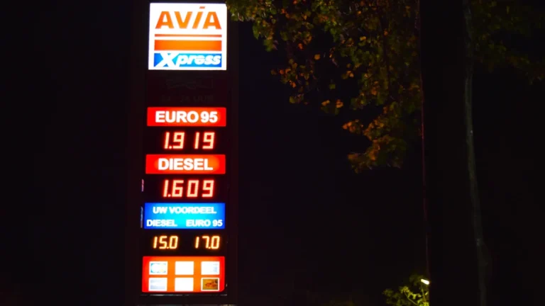 A brightly lit digital price sign at a European petrol station displaying fuel costs.