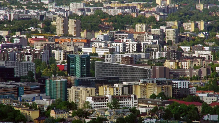 A sweeping aerial view of the Vilnius city skyline showing a mix of modern and residential architecture.