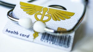 A stethoscope resting on a health insurance card, representing employee medical benefits and healthcare coverage.