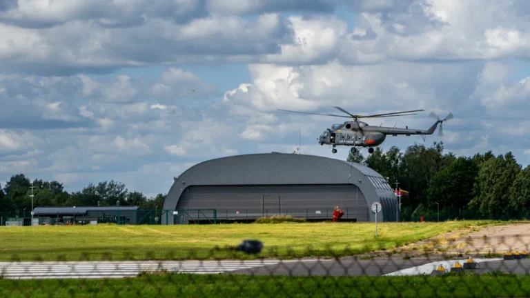 A Lithuanian military helicopter taking off from an airfield, representing the nation's defense modernization.