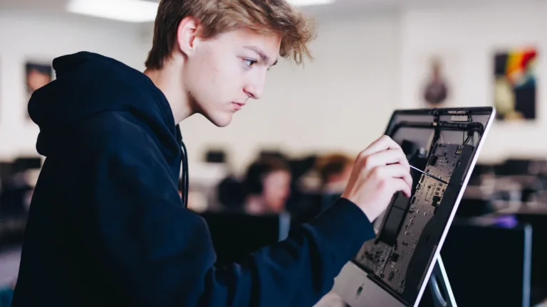 A student in a modern classroom focused on examining the hardware components of a computer, representing Lithuania's Digitalization 3.0 initiative.