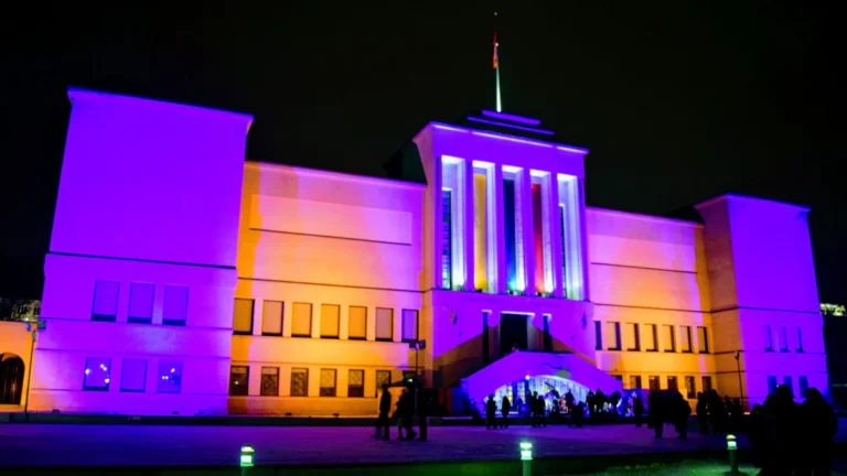 The Vytautas the Great War Museum in Kaunas, Lithuania, illuminated in purple light, symbolizing domestic violence awareness.