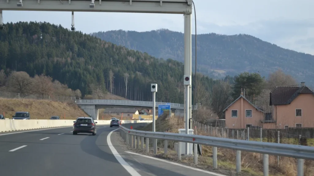 A highway gantry equipped with traffic monitoring cameras and sensors to detect vehicle movement.