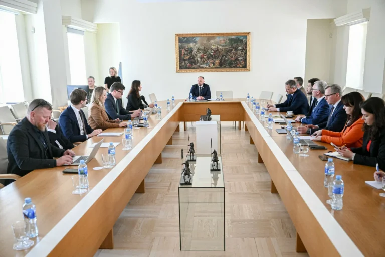 Professionals seated at a large U-shaped table for a formal meeting in a bright conference room.