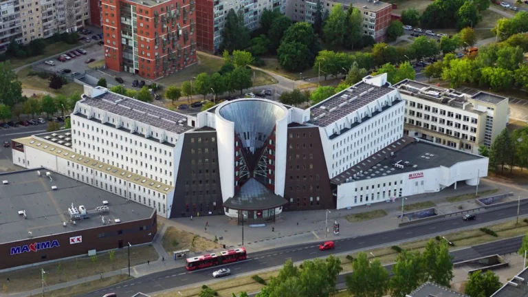 An aerial view of a modern white building with a unique circular architectural feature in Vilnius, Lithuania, representing the new Partnership Center.
