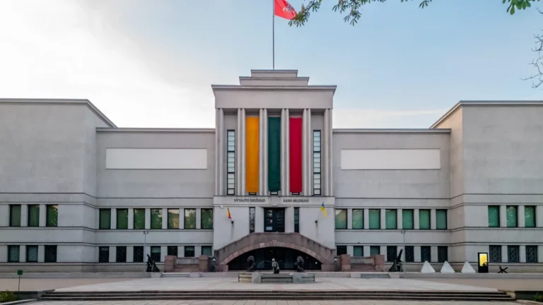 A stately white public building in Lithuania with the national flag displayed prominently on the facade.