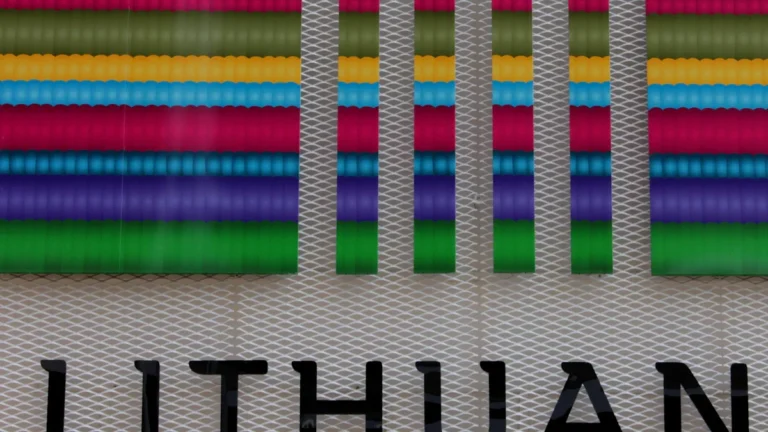 A close-up of a wall featuring the word 'LITHUAN' beneath vibrant, colorful horizontal stripes.