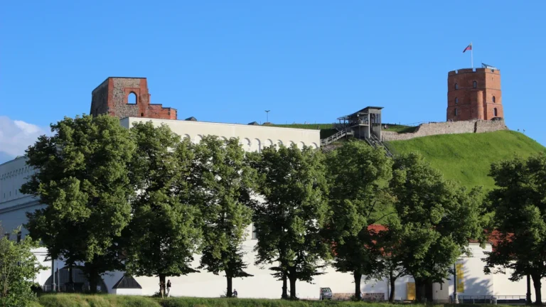 The historic brick Gediminas Tower stands on a green hill overlooking the city of Vilnius, Lithuania.