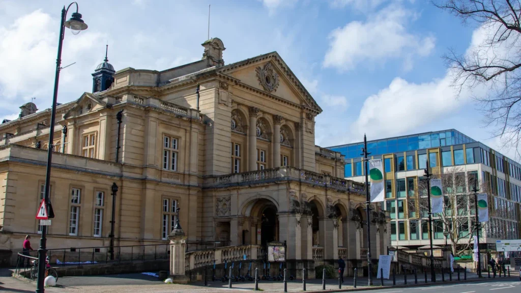 A wide view of a grand historic stone civic building with classical columns under a blue sky.