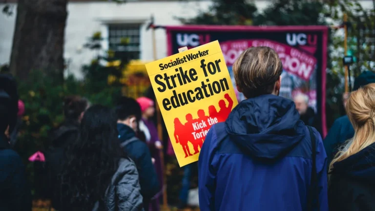 A protester holds a yellow 'Strike for education' sign during a rally for school support staff.