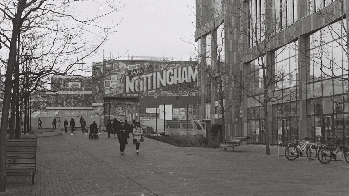 Pedestrians walk past a prominent Nottingham sign in a bustling urban city square.