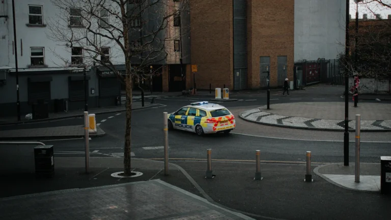 A UK police car with high-visibility Battenburg markings patrolling a street in Nottingham city centre.